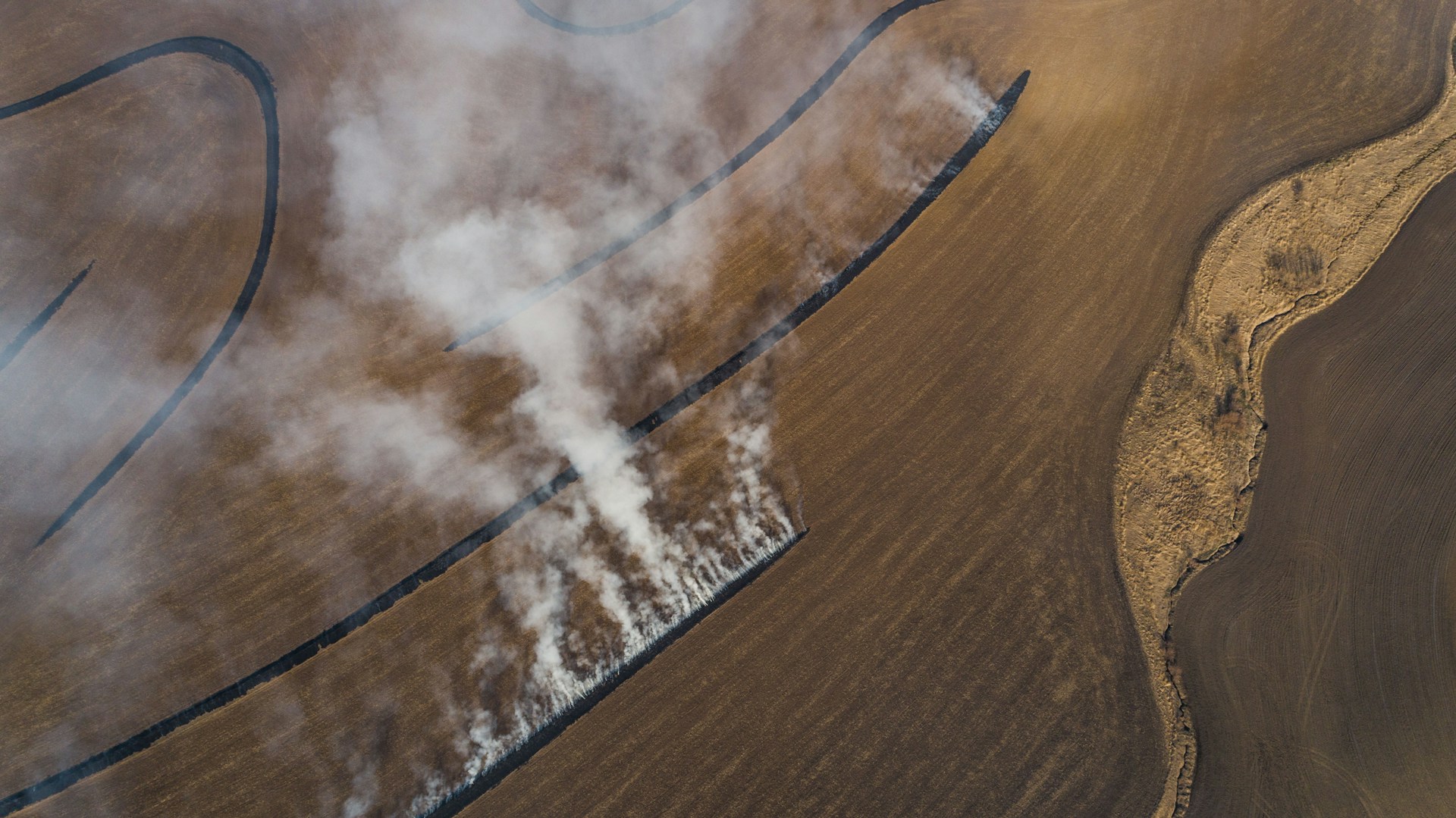 Aerial shot of terraces burning with tall pillars of smoke